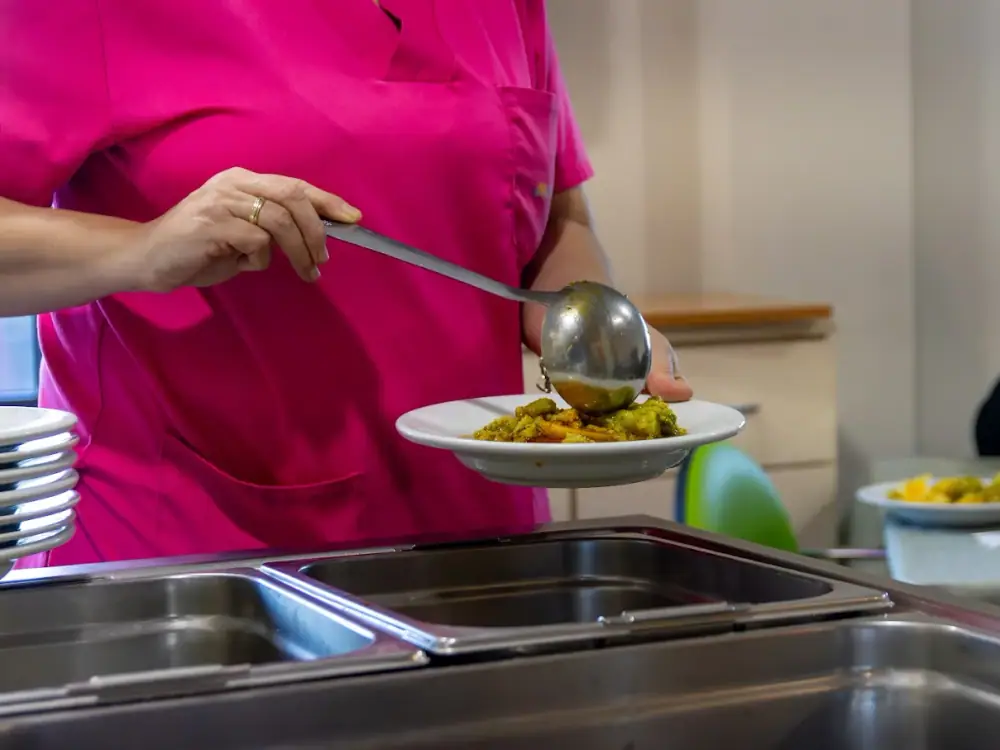 Una cocinera sirve un plato de comida casera en la cocina del centro