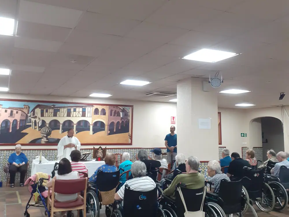Salón de Mejora Navalmoral, con el mural de la pared, durante una celebración con los residentes