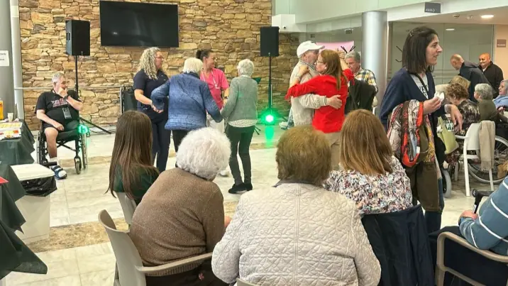 Residentes, familiares y personal bailando en el salón durante la fiesta de San Juan