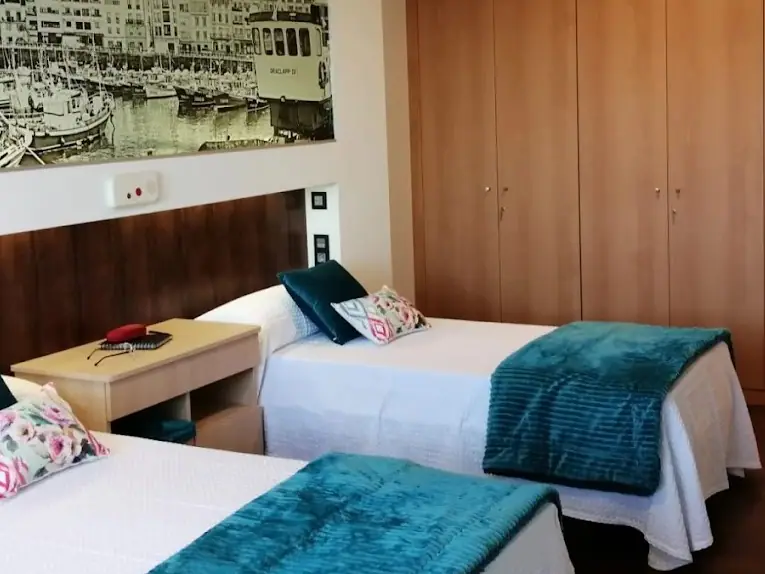 Habitación individual con cama articulada, armario y colcha verde