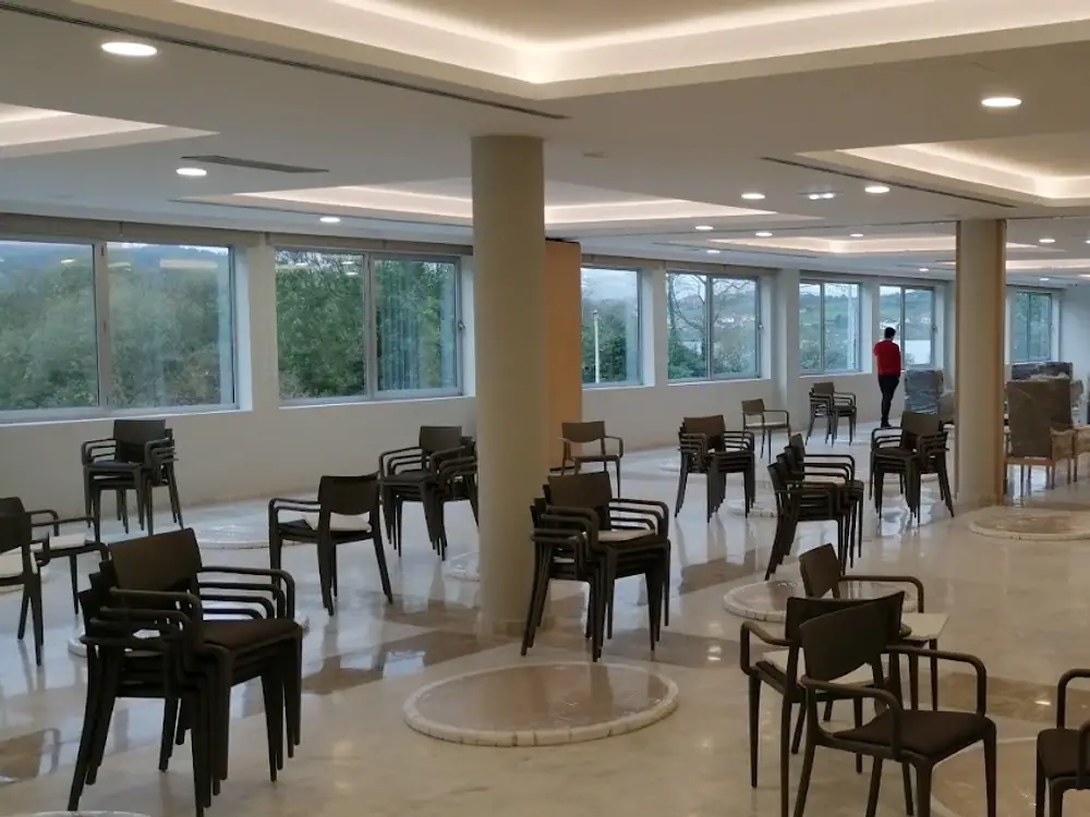 Sala común luminosa con mesas y sillas junto a los ventanales