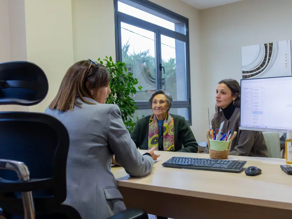 Dos profesionales del centro atienden a una persona en un despacho