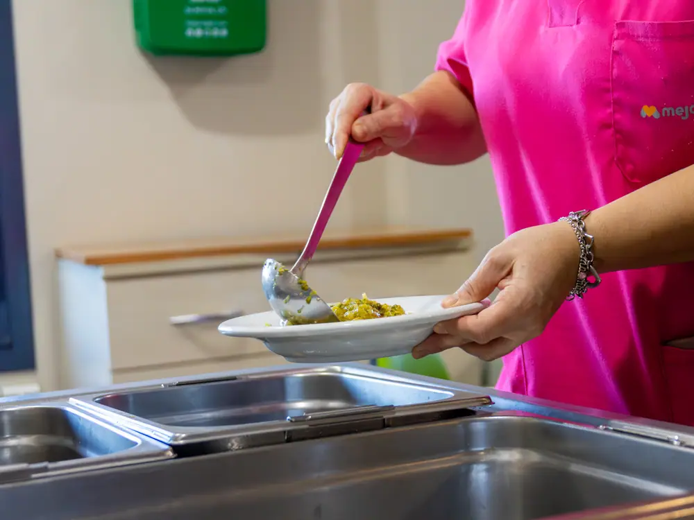 Una cocinera sirve un plato de comida casera